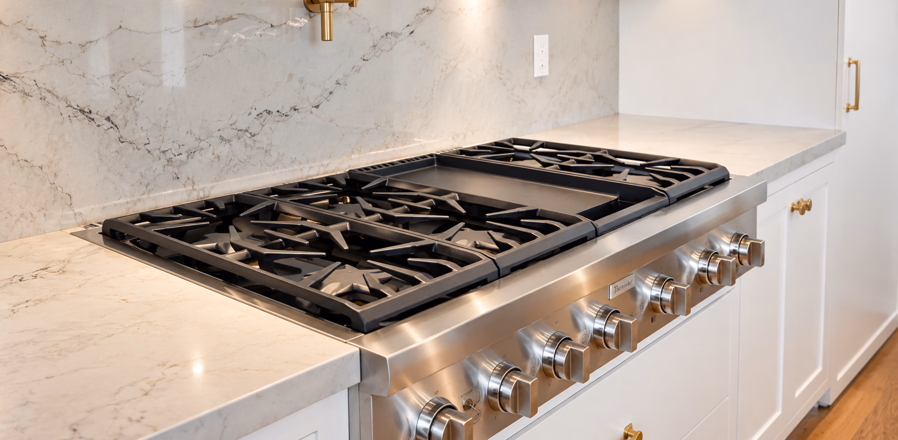 Stainless rangetop set into stone counters and a slab backsplash